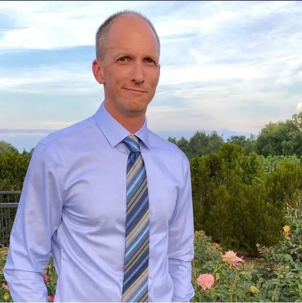 Mathew Black, Founder of MB Systems Group, in a shirt and tie, photographed outdoors at dusk.